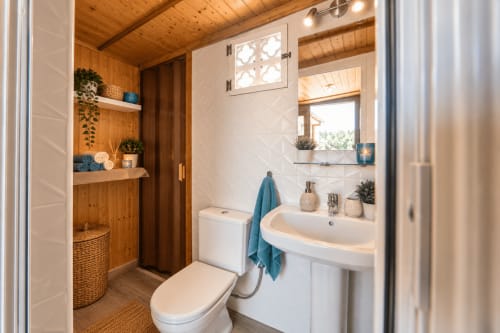 Bagno luminoso a Sara & Gino Fuerteventura con accenti in legno, lavabo bianco, toilette, specchio e asciugamani turchesi