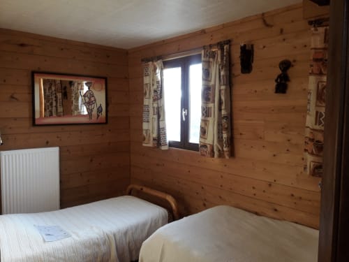 Chambre chaleureuse à La Ferme Buissonnière avec deux lits, radiateur, fenêtre et décor rustique