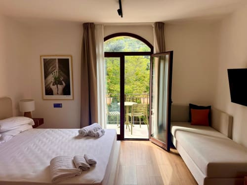 Camera moderna presso Dimora Silva con letti gemelli, porte-finestre ad arco che si aprono su una splendida vista del verde, e arredi contemporanei