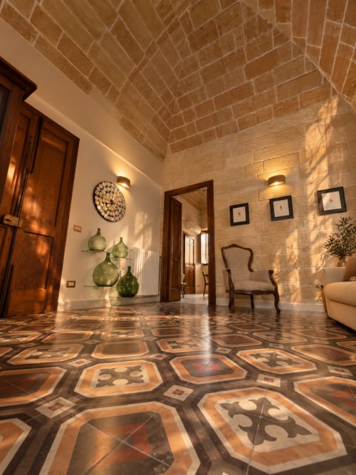 Elegant hallway at HABITARE Lecce with decorative tile floor, exposed brick vaulted ceiling, wooden doors, and contemporary