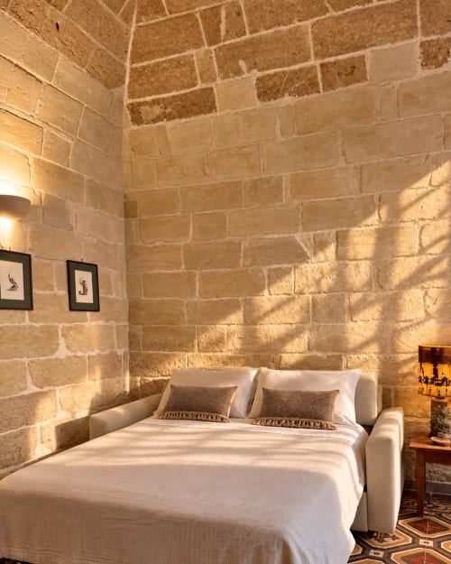 Bright bedroom at HABITARE Lecce with stone walls, white bed, and natural light in Salento, Italy