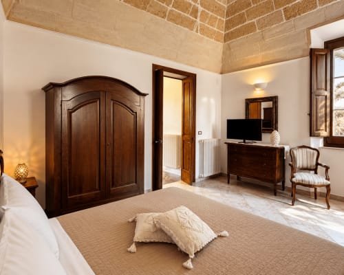 Spacious bedroom at HABITARE Lecce with wooden wardrobe, TV, period furniture and city views in Salento, Italy