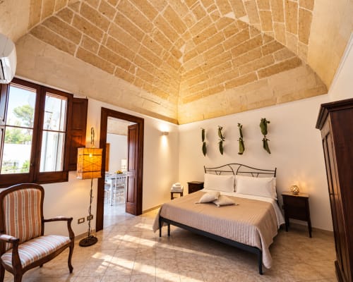 Spacious bedroom at HABITARE Lecce with vaulted brick ceiling, wooden beams, bed, and city views