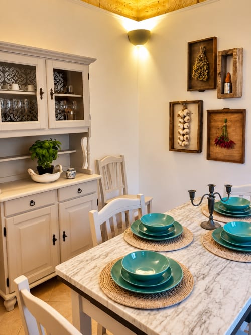 Elegant dining area in HABITARE Lecce apartment with marble table, turquoise dinnerware, and vintage wall décor