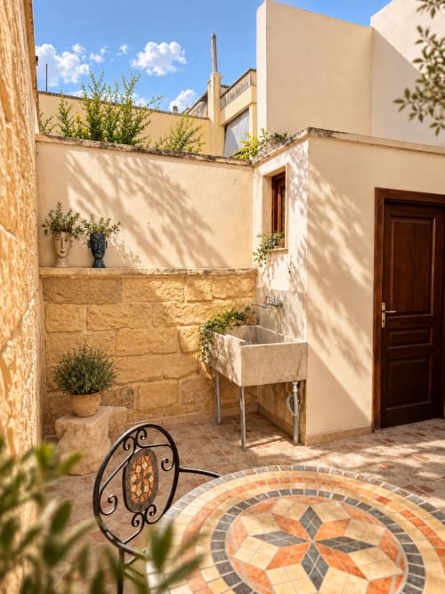 Charming courtyard at HABITARE Lecce with stone walls, mosaic floor, and traditional wooden door