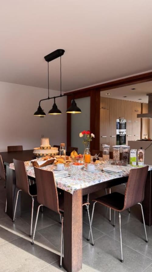 Sala de jantar moderna na Quinta Trindade em Arouca com mesa de madeira, iluminação pendente e vista aberta para a cozinha