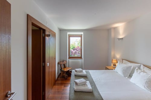 Espaçoso quarto de casal na Quinta Trindade com vista para a montanha, portas de madeira, roupa de cama branca e vista ao jardim