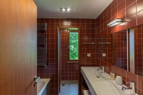 Casa de banho moderna na Quinta Trindade em Arouca com azulejos vermelhos, dupla bacia, duche e vista para o jardim