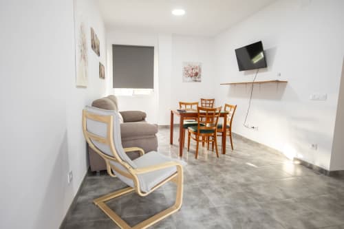 Luminosa sala de estar en Hostal Restaurante Atalaya en Minas de Riotinto con mesa de comedor, sillas de madera y ambiente acogedor