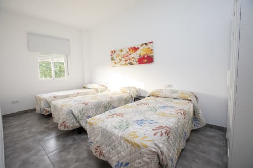 Habitación luminosa en Hostal Restaurante Atalaya en Minas de Riotinto con tres camas de ropa de cama floral colorida