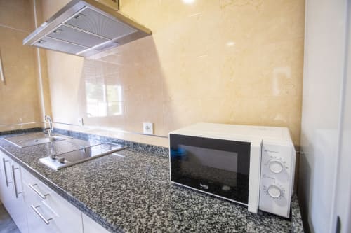 Cocina moderna en apartamento de Hostal Restaurante Atalaya con encimeras de granito, microondas y fregadero de acero inoxidable en Minas