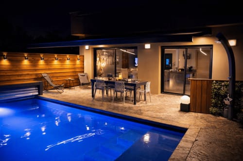 Piscine chauffée de nuit avec terrasse de villa illuminée, coin repas et transats à Corsu Di Core à Favona