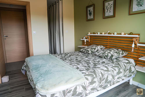 Chambre spacieuse à la Villa Core di Favona avec lit en bois, parure motifs, murs verts et art botanique
