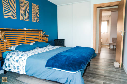 Chambre moderne avec mur d'accent bleu, tête de lit en bois rayé et literie à motifs à Villa Core di Favona, Corse