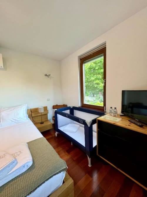 Quarto duplo de luxo na Quinta Trindade com cama de casal, berço, TV e vista para o jardim em Arouca