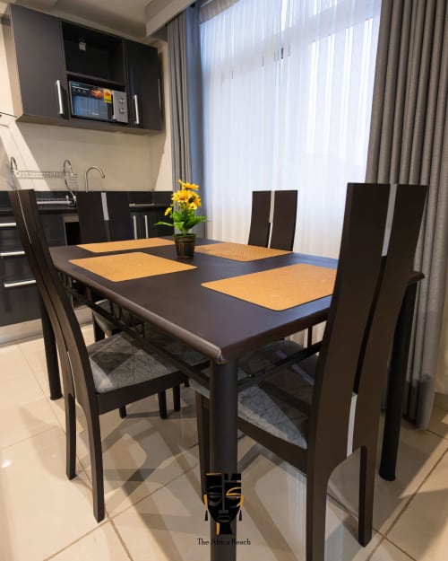Modern dining area at The Africa Reach, Accra with black table, yellow placemats, and dark chairs