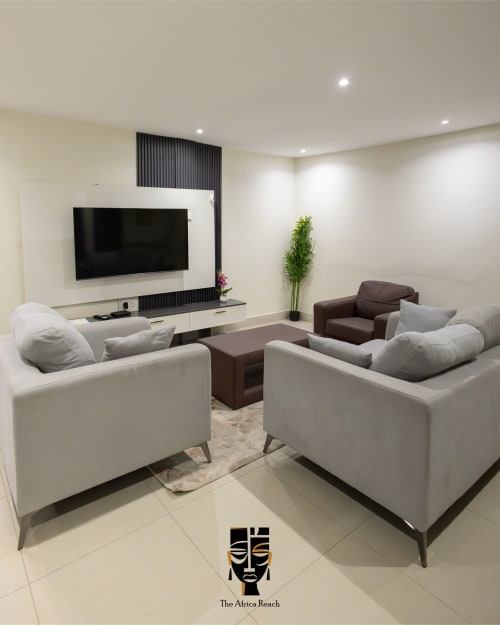 Modern living room at The Africa Reach, Accra with white sofas, flat-screen TV, and contemporary decor