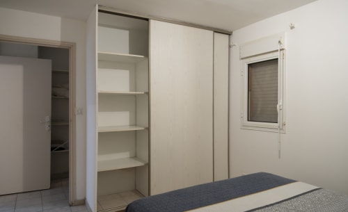 Chambre moderne avec armoire coulissante blanche, rangements intégrés et lit au NGAYABE 976 à Mamoudzou