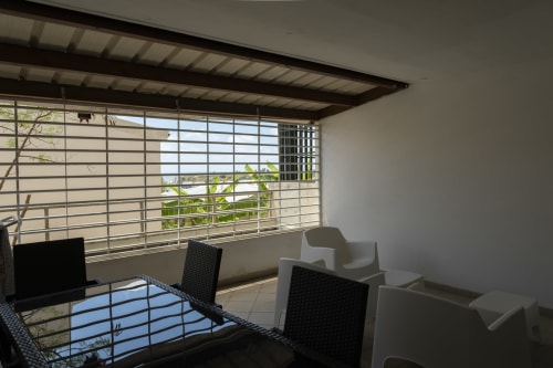 Terrasse couverte de l'appartement NGAYABE 976 à Mamoudzou avec vue mer, mobilier moderne et paysage océanique