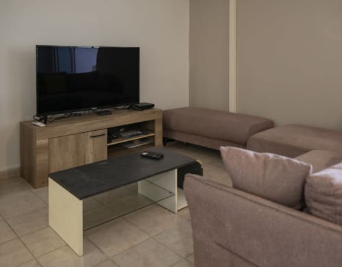 Salon moderne de l'appartement NGAYABE 976 avec canapé sectionnel marron, meuble TV en bois et table basse noire à Mamoudzou
