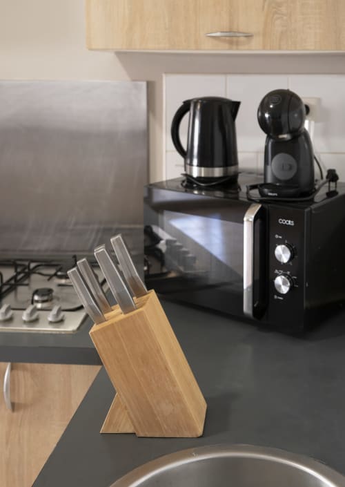 Comptoir de cuisine moderne dans l'appartement de Mamoudzou avec porte-couteaux en bois, micro-ondes, bouilloire électrique et cafetière