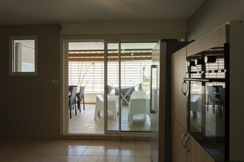 Séjour moderne à NGAYABE 976, Mamoudzou, avec portes coulissantes vitrées ouvrant sur terrasse couverte et vue mer