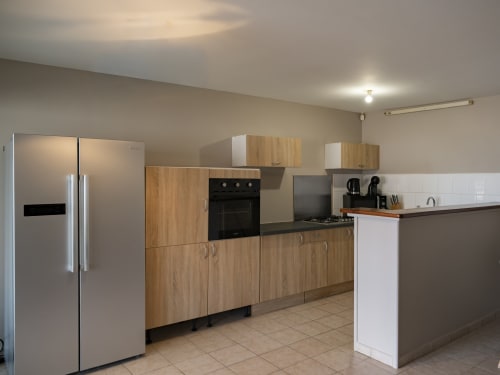 Cuisine moderne de l'appartement CP204 à l'hôtel NGAYABE 976 à Mamoudzou avec armoires en bois, appareils en acier inoxydable et