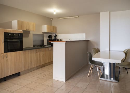 Cuisine moderne et salle à manger de l'appartement CP204 à NGAYABE 976, Mamoudzou avec meubles en bois et îlot