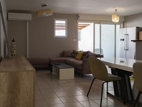 Appartement moderne à Mamoudzou avec canapé marron, salle à manger, cuisine et balcon vue sur mer