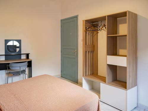 Chambre moderne à NGAYABE 976 à Mamoudzou avec armoire en bois, bureau de travail et vue sur la ville