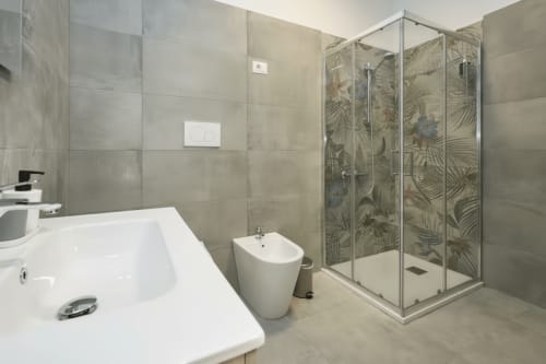 Bagno moderno dell'appartamento AirFlat Yellow House a Rozzano con lavabo bianco, bidet e cabina doccia in vetro