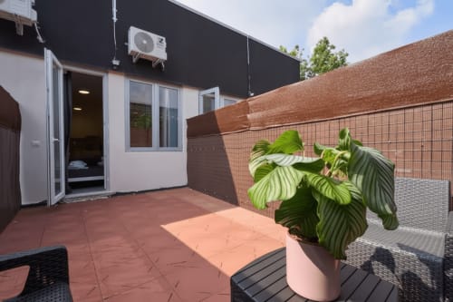 Terrazza soleggiata dell'appartamento Yellow House a Rozzano con pianta in vaso, muri in mattone e unità AC