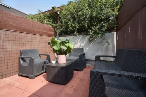 Terrazza esterna dell'appartamento Yellow House a Rozzano con mobili in rattan e piante in vaso con vista sulla corte in mattoni