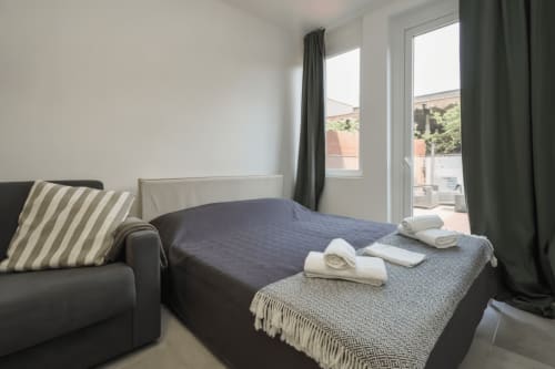 Camera moderna in AirFlat Yellow House, Rozzano con letto, cuscino rigato, tende scure, accesso al balcone e asciugamani arrotolati