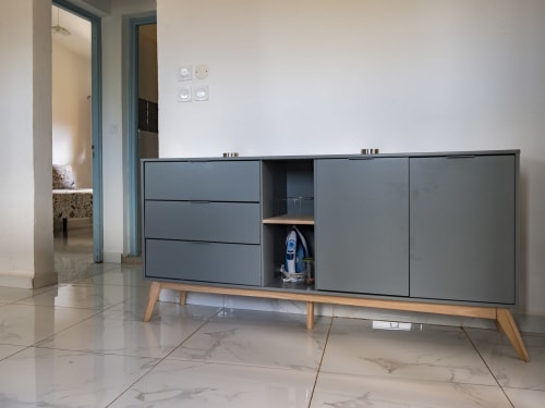 Meuble de rangement gris moderne aux pieds en bois avec étagère ouverte exposant un fer à repasser dans l'appartement NGAYABE 976, Mamoudzou
