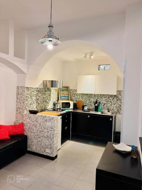 Angolo cottura moderno con rivestimento a mosaico, mobili neri e soffitto arcato nell'appartamento La Superba Stay Genova