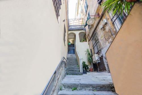 Stretto vicolo con gradini in pietra che conducono all'ingresso di un edificio genovese tradizionale, La Superba Stay Genova