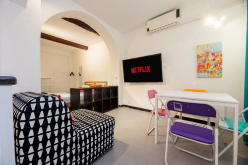 Moderno monolocale in La Superba Stay Genova con TV Netflix, divano a motivi geometrici, scrivania bianca e arcata