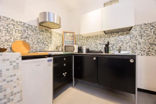Moderna cucina nell'appartamento Balbi di La Superba Stay Genova con rivestimento a mosaico, mobili neri e acciaio inox