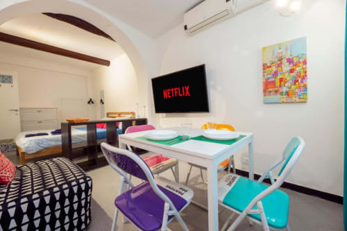 Luminoso appartamento moderno a La Superba Stay Genova con tavolo da pranzo, TV, sedie colorate, letto e angolo cucina in open space