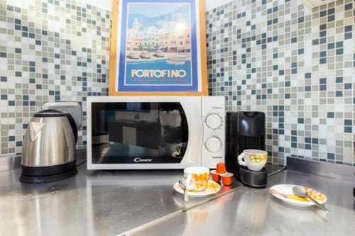 Angolo cottura a Genova con microonde, bollitore e macchina da caffè su bancone con piastrelle mosaico