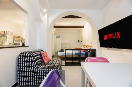 Moderno monolocale a Genova con angolo cottura, divano decorato, TV a schermo piatto con Netflix e ingresso ad arco