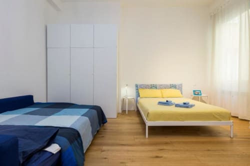 Luminosa camera da letto in studio a La Superba Stay Genova con letti blu e gialli, pavimenti in legno, armadio bianco e