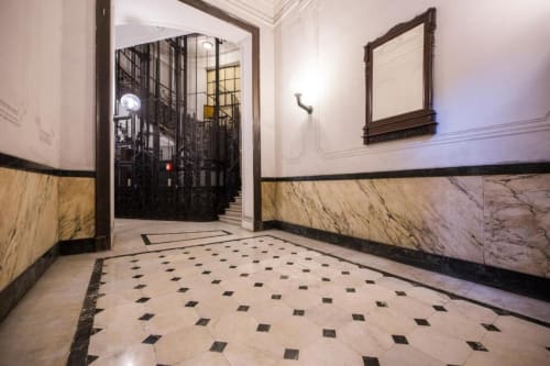 Elegante ingresso della La Superba Stay Genova con rivestimento in marmo, pavimentazione geometrica e porte in ferro battuto
