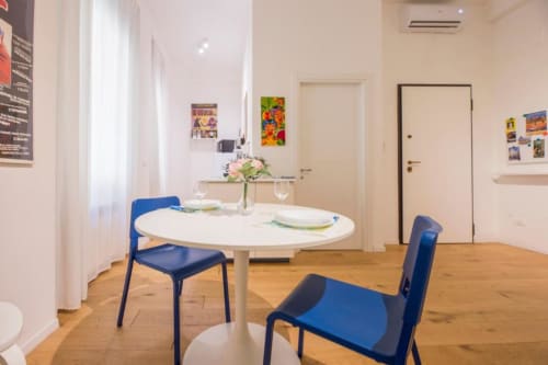 Zona pranzo moderna nell'appartamento studio La Superba Stay Genova con tavolo rotondo bianco, sedie blu e pavimentazione in legno