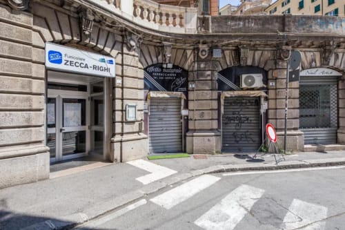Veduta della strada dell'ingresso dell'appartamento La Superba Stay a Genova nella storica città, con vetrine scuri e pietra