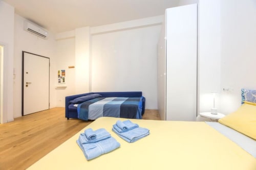 Luminoso monolocale a La Superba Stay Genova con letto matrimoniale, divano-letto blu, pavimenti in legno e servizi moderni