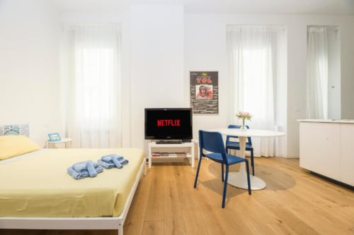 Moderno monolocale a Genova con letto, TV Netflix, tavolo da pranzo, sedia blu, parquet e luce naturale