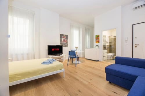 Accogliente monolocale a La Superba Stay Genova con letto giallo, divano blu, TV con Netflix, pavimenti in legno