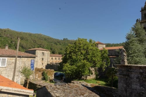 Hotel Casiña D'Avoa en Osera, España - edificios de piedra en ladera verde con arquitectura tradicional